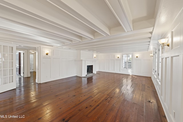 unfurnished living room featuring dark wood-style floors, a fireplace, a decorative wall, and beam ceiling