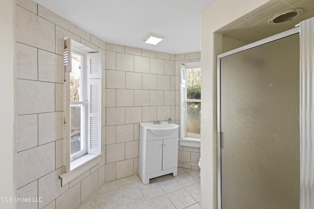 bathroom with a shower stall, vanity, tile walls, and tile patterned floors