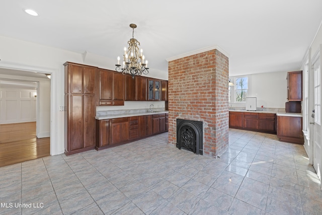 kitchen featuring light tile patterned flooring, a fireplace, a sink, light countertops, and hanging light fixtures