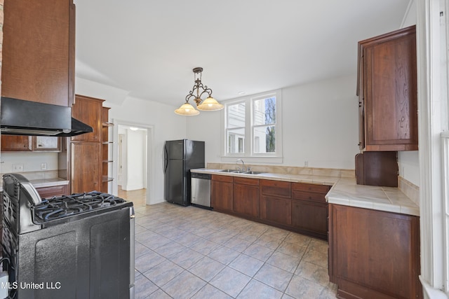 kitchen featuring pendant lighting, tile counters, an inviting chandelier, a sink, and black appliances