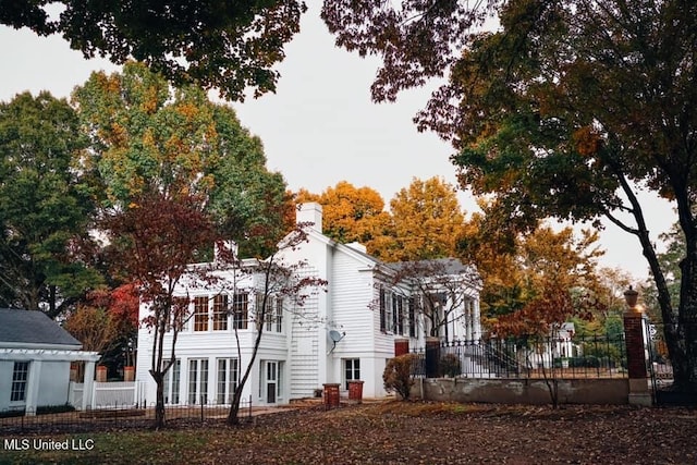 view of side of home with a chimney and fence