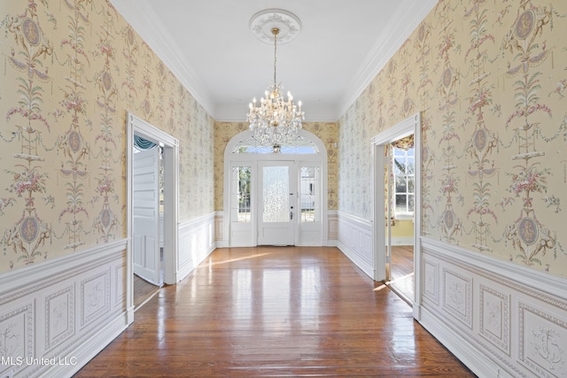 entryway featuring wallpapered walls, crown molding, a wainscoted wall, and wood finished floors