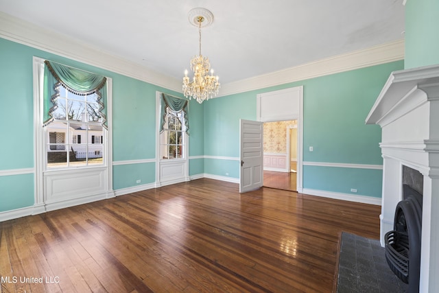 unfurnished living room with baseboards, wood-type flooring, a fireplace with flush hearth, ornamental molding, and an inviting chandelier