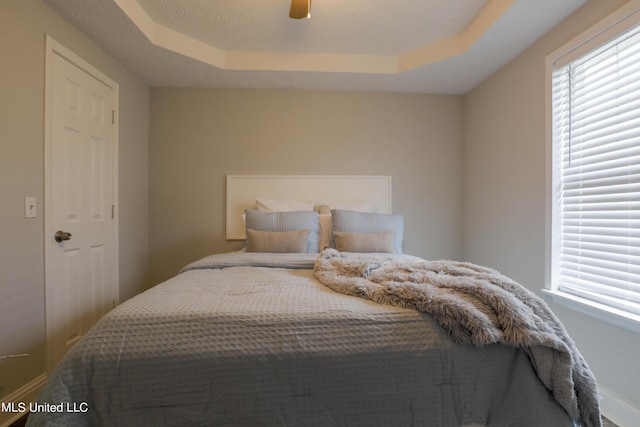 bedroom featuring a raised ceiling and ceiling fan