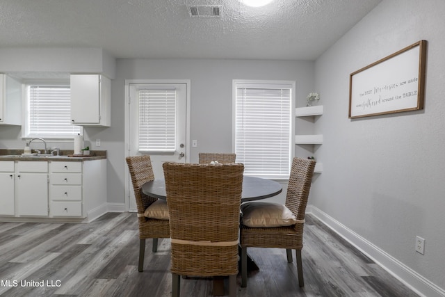 dining space featuring sink, a textured ceiling, and light wood-type flooring