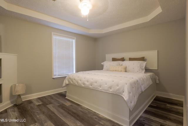 bedroom featuring a textured ceiling, dark hardwood / wood-style floors, a raised ceiling, and ceiling fan