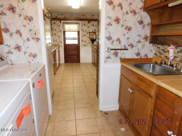 kitchen featuring sink, washing machine and clothes dryer, and light tile patterned floors