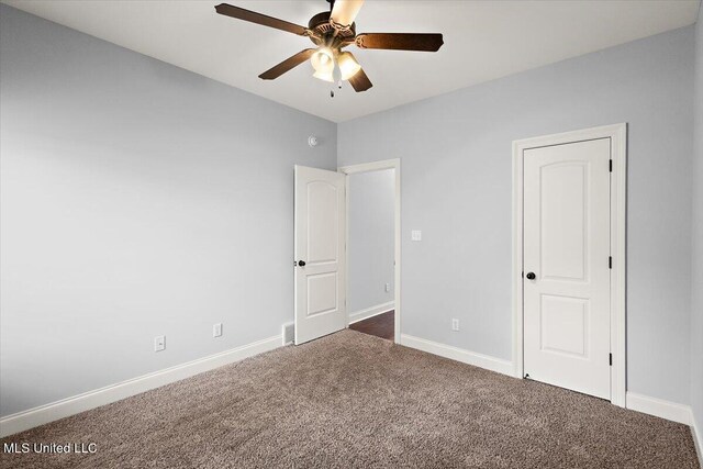 unfurnished bedroom featuring ceiling fan and dark carpet