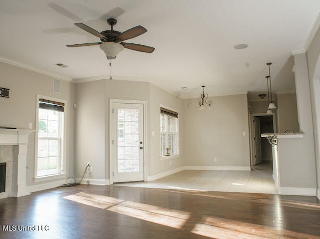 unfurnished living room with a fireplace, ceiling fan with notable chandelier, light hardwood / wood-style flooring, and ornamental molding