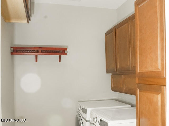 laundry room featuring washing machine and dryer and cabinets