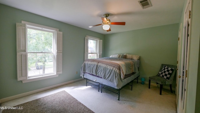 bedroom featuring multiple windows, light colored carpet, and ceiling fan