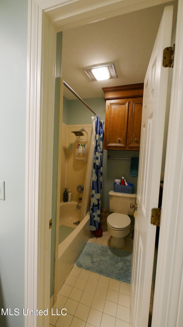 bathroom featuring shower / bath combo with shower curtain, toilet, and tile patterned floors