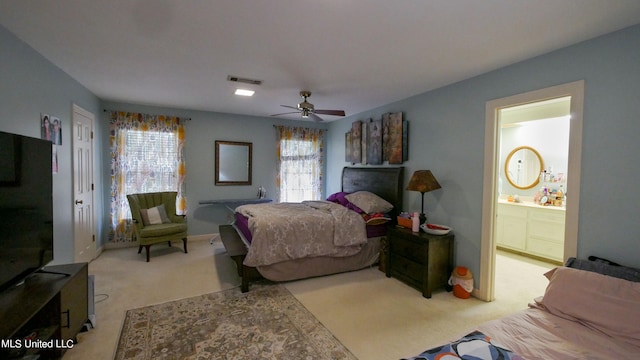 carpeted bedroom featuring ceiling fan, multiple windows, and ensuite bathroom