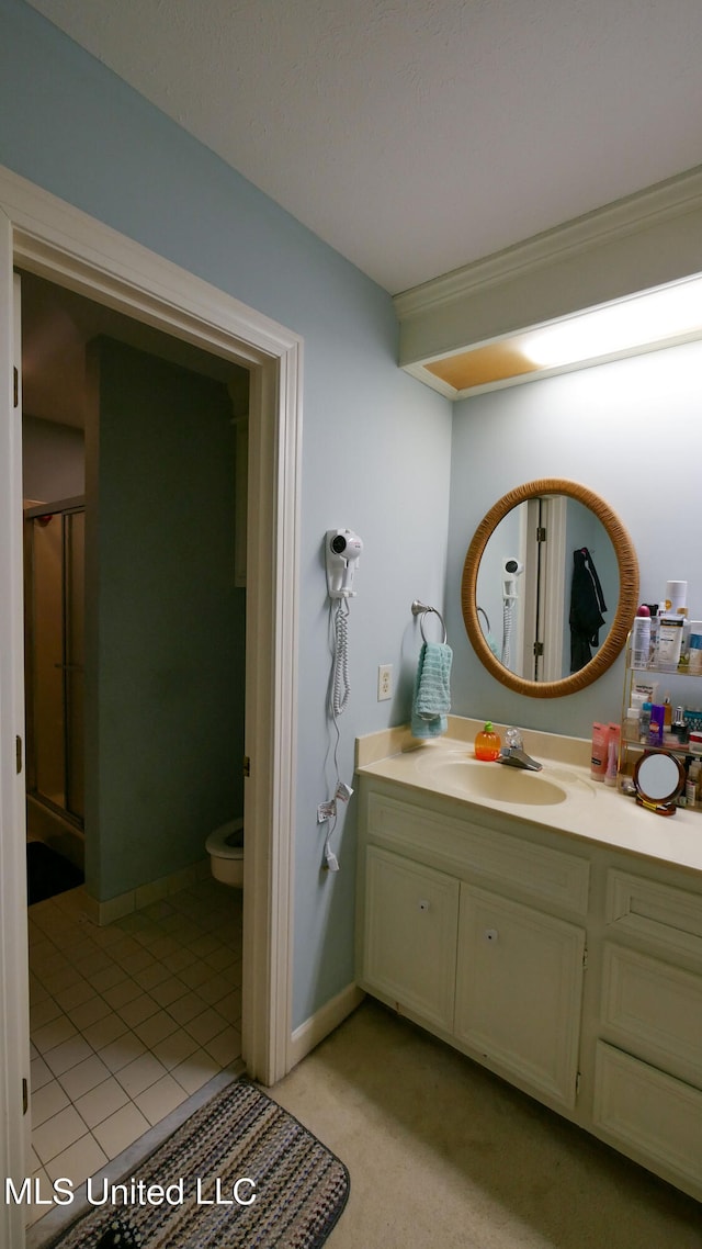 bathroom with vanity, toilet, tile patterned floors, and a shower with door