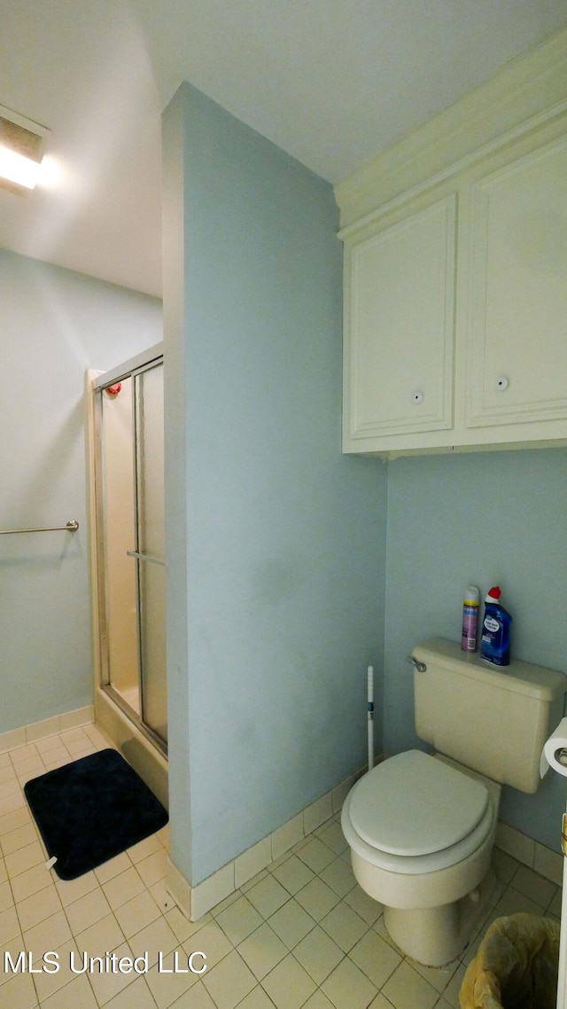 bathroom featuring toilet, an enclosed shower, and tile patterned flooring