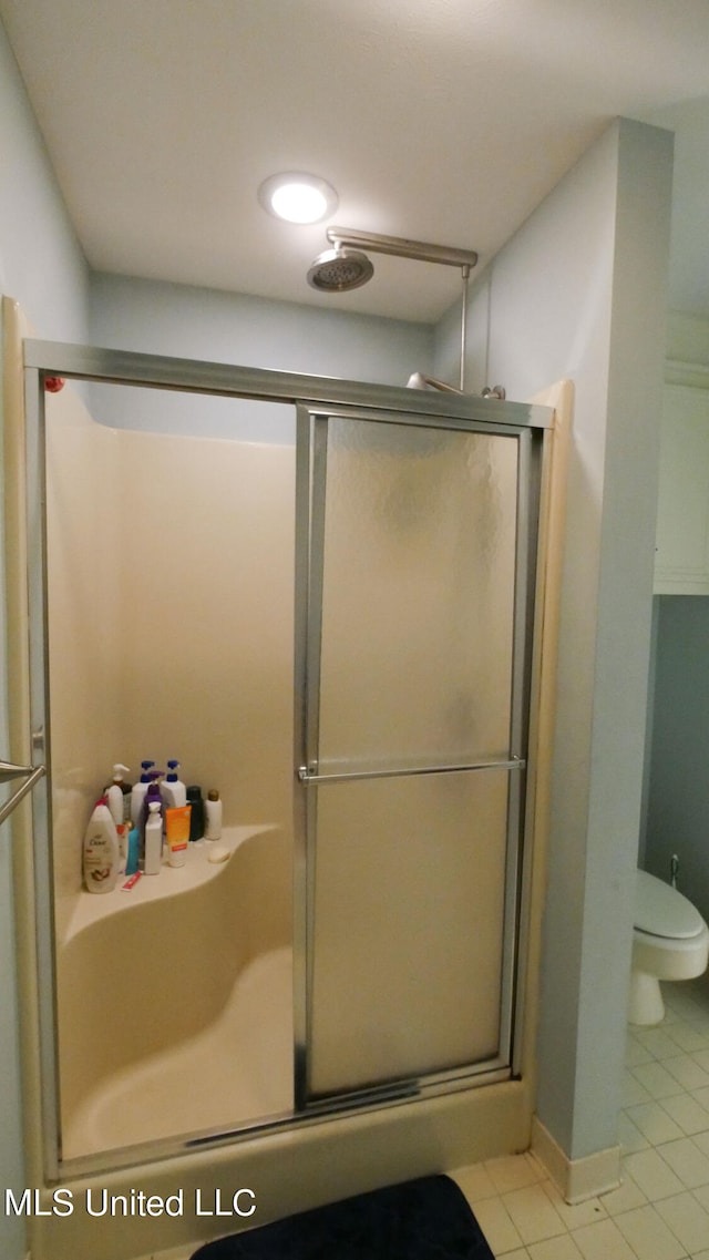 bathroom with tile patterned floors, toilet, and an enclosed shower