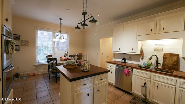 kitchen featuring sink, appliances with stainless steel finishes, pendant lighting, and wood counters