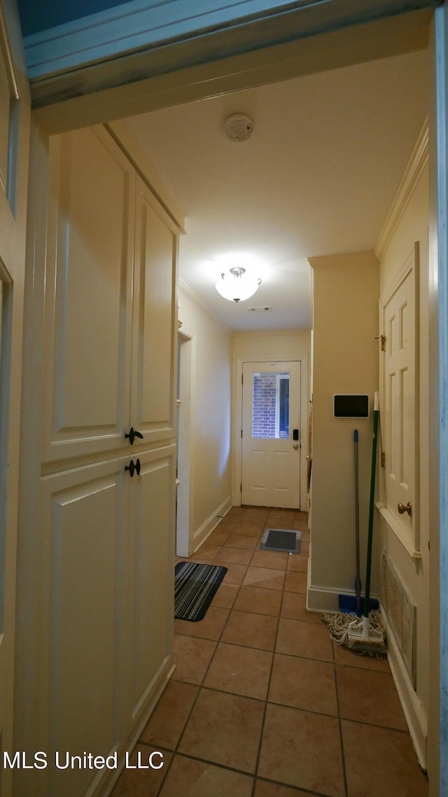 hallway with crown molding and tile patterned flooring