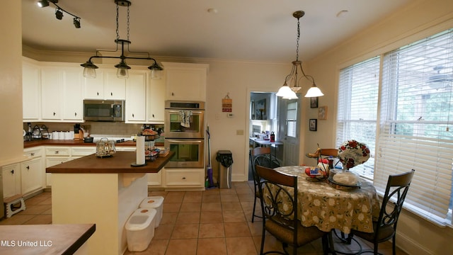 kitchen featuring crown molding, white cabinets, stainless steel appliances, and pendant lighting