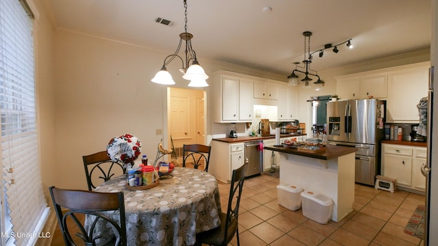 kitchen featuring a kitchen island, hanging light fixtures, ornamental molding, white cabinets, and appliances with stainless steel finishes