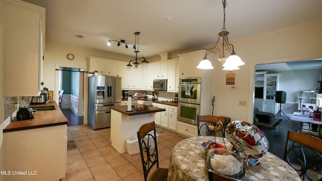 kitchen featuring a kitchen island, hanging light fixtures, white cabinetry, stainless steel appliances, and a chandelier