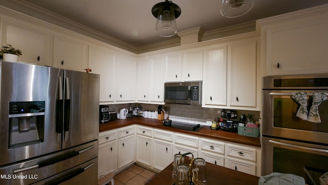 kitchen with backsplash, appliances with stainless steel finishes, white cabinetry, light tile patterned flooring, and crown molding