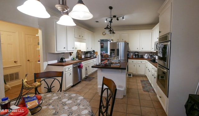 kitchen featuring sink, pendant lighting, white cabinetry, light tile patterned floors, and appliances with stainless steel finishes