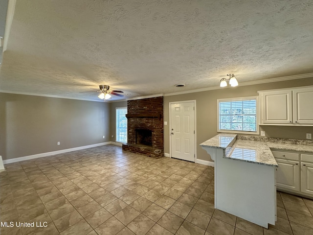 unfurnished living room with a textured ceiling, a fireplace, light tile patterned floors, ceiling fan with notable chandelier, and ornamental molding