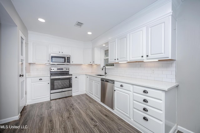 kitchen with stainless steel appliances, sink, tasteful backsplash, dark wood-type flooring, and white cabinets