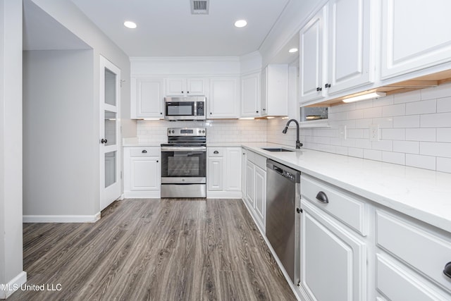 kitchen featuring white cabinetry, hardwood / wood-style flooring, stainless steel appliances, light stone countertops, and sink