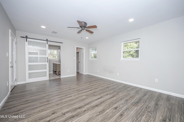 spare room with a healthy amount of sunlight, dark hardwood / wood-style flooring, and a barn door