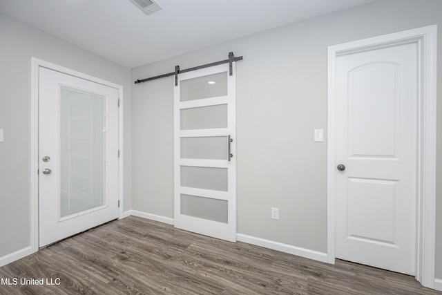 empty room featuring a barn door and dark hardwood / wood-style floors