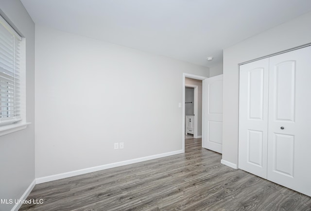 unfurnished bedroom with a closet and dark hardwood / wood-style flooring