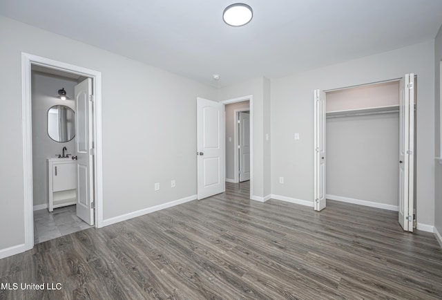 unfurnished bedroom featuring dark hardwood / wood-style flooring, sink, ensuite bath, and a closet