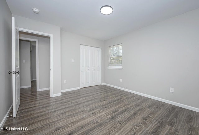 unfurnished bedroom with a closet and dark hardwood / wood-style flooring