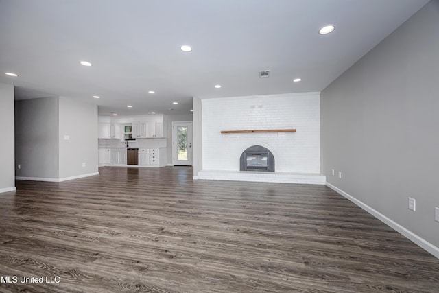 unfurnished living room with a fireplace and dark wood-type flooring