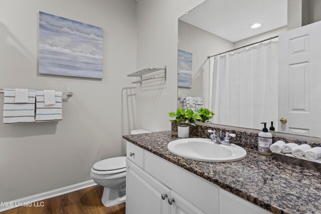 bathroom with toilet, hardwood / wood-style flooring, and vanity