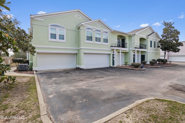 view of front of property featuring central AC unit, a garage, and a balcony