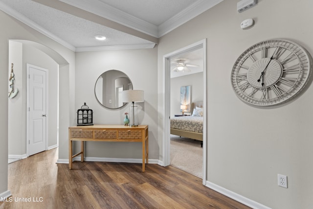 corridor with ornamental molding, dark hardwood / wood-style floors, and a textured ceiling