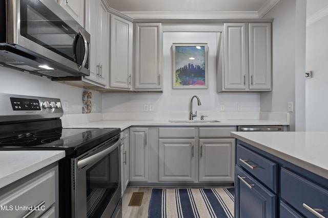 kitchen featuring appliances with stainless steel finishes, dark hardwood / wood-style flooring, ornamental molding, sink, and gray cabinets