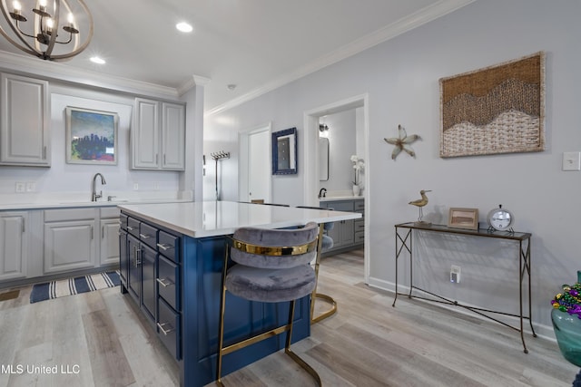 kitchen with a center island, crown molding, sink, light wood-type flooring, and a chandelier