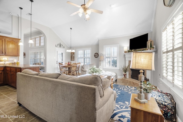 tiled living room with lofted ceiling, ceiling fan, a fireplace, and a healthy amount of sunlight