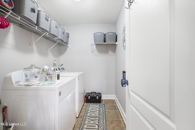 laundry area with dark tile patterned floors, separate washer and dryer, and a textured ceiling