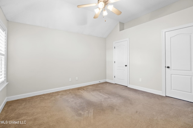 carpeted spare room featuring lofted ceiling and ceiling fan