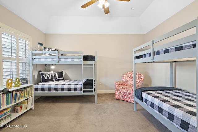 bedroom with a raised ceiling, vaulted ceiling, carpet floors, and ceiling fan