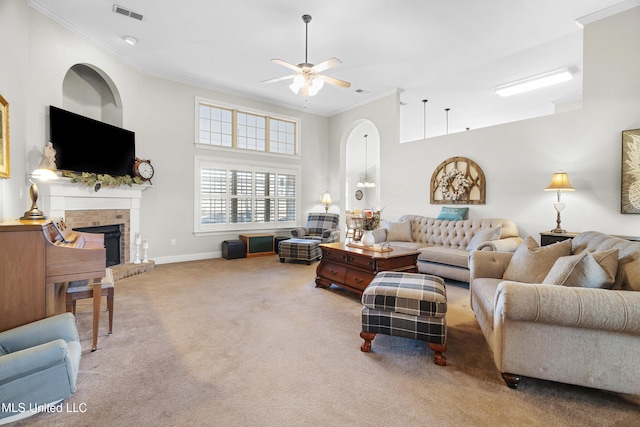 carpeted living room featuring a brick fireplace, ornamental molding, and ceiling fan