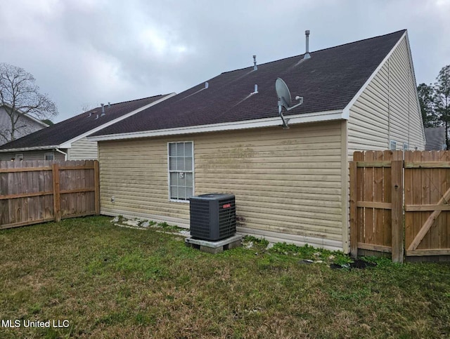 back of property featuring central AC unit and a yard