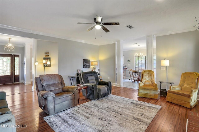 living room with crown molding, wood-type flooring, a wealth of natural light, and ceiling fan with notable chandelier