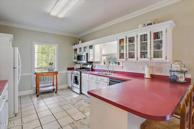 kitchen with kitchen peninsula, stainless steel appliances, backsplash, sink, and white cabinetry