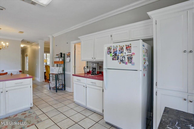 kitchen featuring white fridge, crown molding, light tile patterned floors, and white cabinets